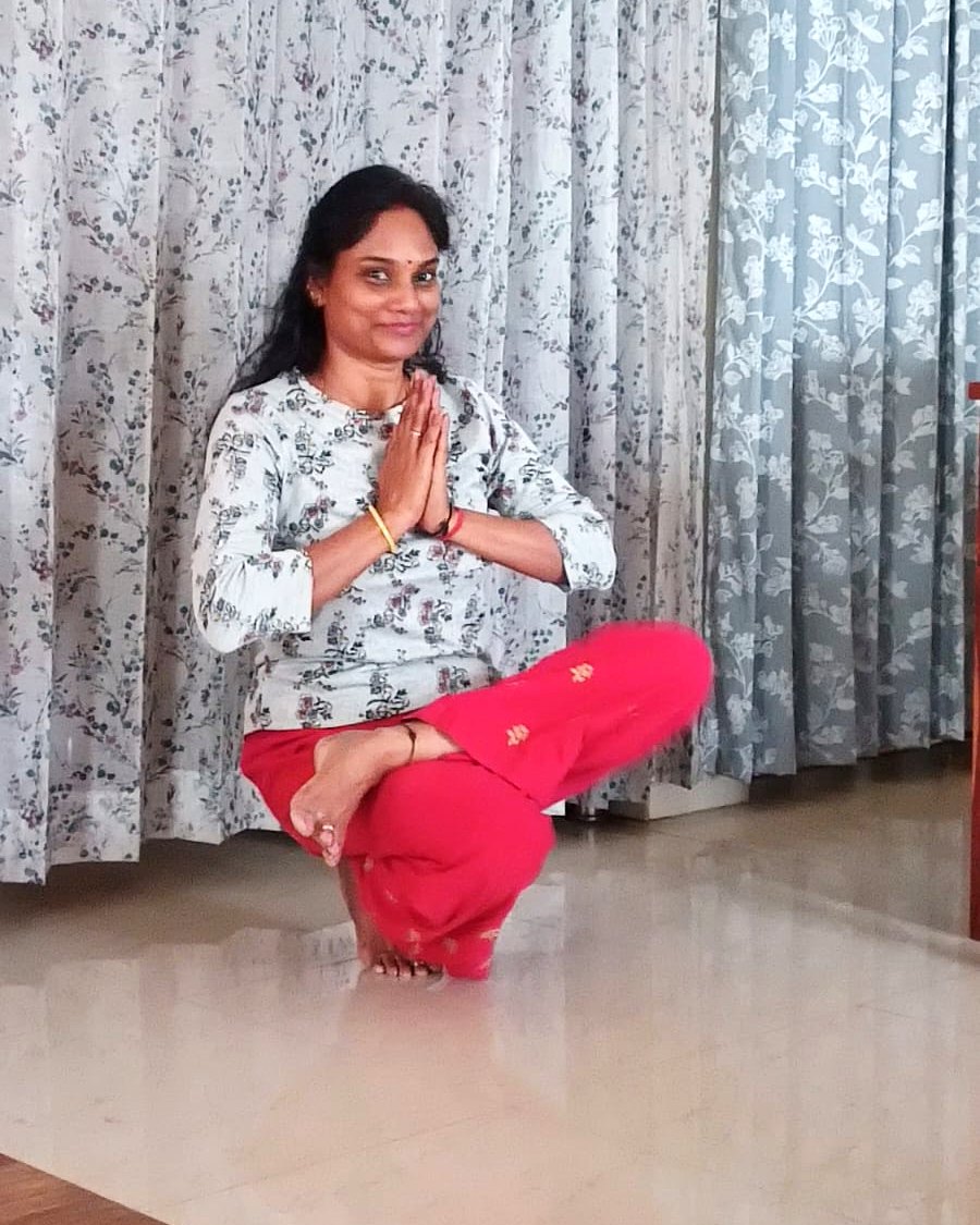 Jyoti seated in namaste at home, mid-class
